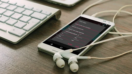 Fuel Music Player app on desk with keyboard and earphones showing dark theme music interface and controls