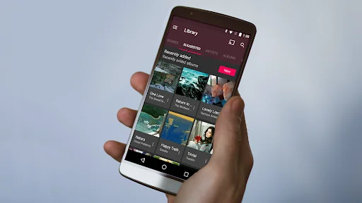 Hand holding phone with Fuel Music Player Library screen showing album grid view with colorful album artwork